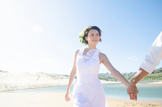ビーチで手をつないでいるドレス姿の女性