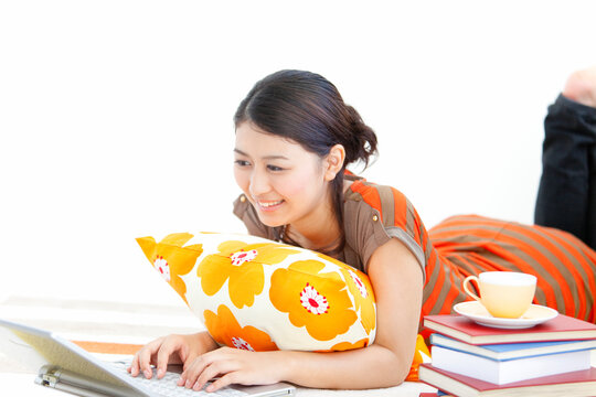 うつ伏せでノートパソコンを操作する女性