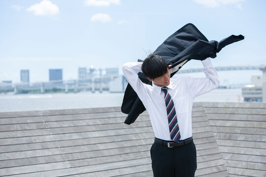 屋上でスーツを着る20代男性