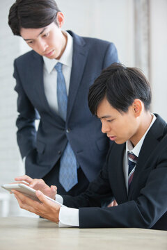 タブレットを使い説明を受けるスーツ姿の男性
