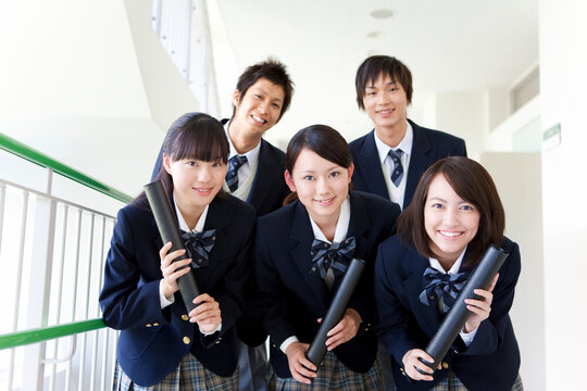 卒業証書が入った筒を持っている学生5人