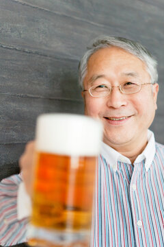 ビールで乾杯のポーズをするシニア男性