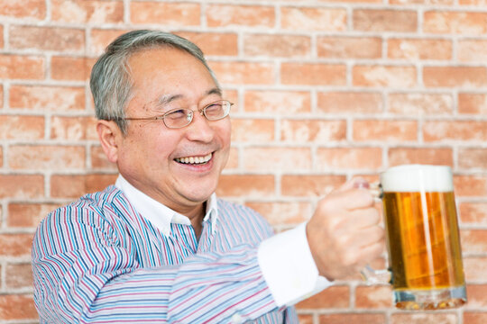 ビールで乾杯のポーズをするシニア男性