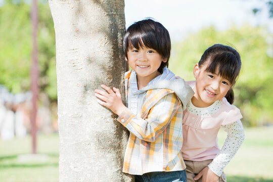 木の横に立つ男の子と女の子