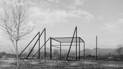 Black and white shot of a field with a pipe structure and mountains in the background