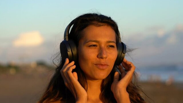 Happy, beautiful woman listen to music on the beach
