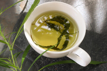 Top view hemp tea in a white cup with cannabis leaf