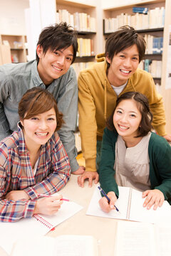 勉強する笑顔の大学生4人