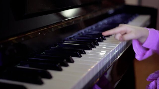 The girl's hand presses the piano keys