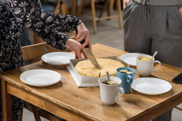 Woman cutting cake with almonds, on a wooden table. Holiday concept