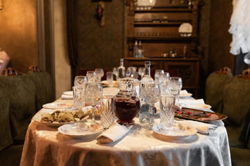Banquet table in the house, preparation for a banquet. Glasses, plates, cutlery