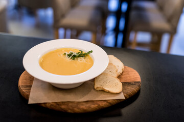 Creamy soup with smoked salmon in a white plate. Health theme. Food in the restaurant. Green...