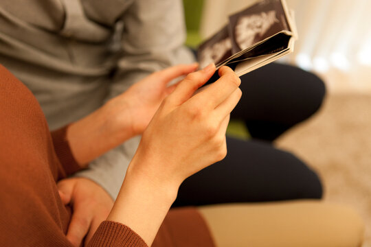 胎児のエコー写真を持つ手