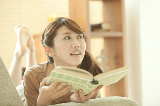 寝転んで本を読む女性