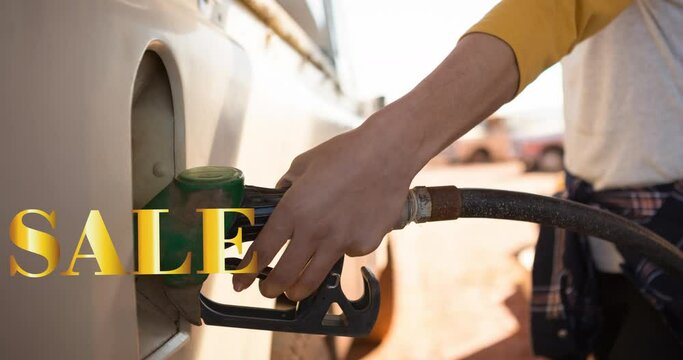 Animation of sale text in gold over midsection of woman using fuel pump at petrol station