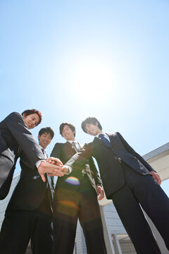 円陣を組むビジネスマン4人