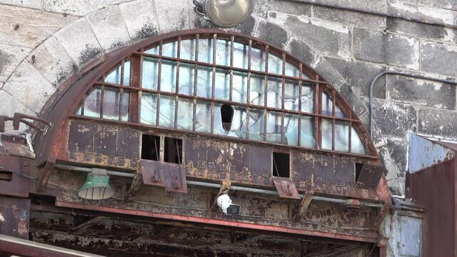 Rusted arched window with cracked glass.