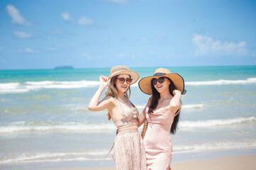 young women Asian and friends enjoying on the beach on a sunny day. Two young women Asian walking together on a beach. young women happy friends at sunset beach party runs to water