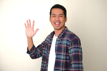 Side view of adult Asian man smiling happy while waving his hand