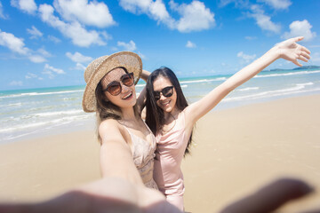Fototapeta premium Beautiful young woman doing selfie on the beach. Relax travel on the beach concept