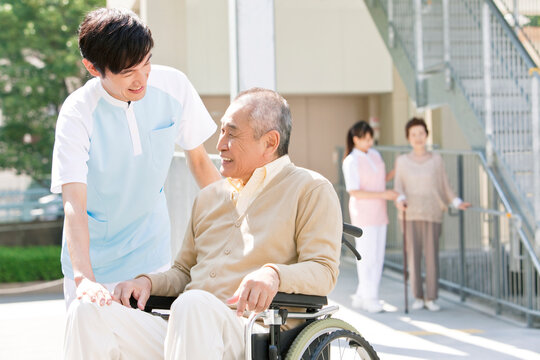 介護士と車いすに乗った中高年男性