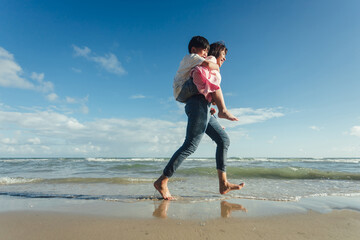 Young happy beautiful mother and her daughter having fun on the beach. Young family asian on vacation have a lot of fun