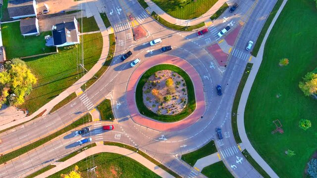 Time lapse traffic flows through beautiful modern roundabout in Autumn morning sunshine, aerial time lapse, seamless loop.