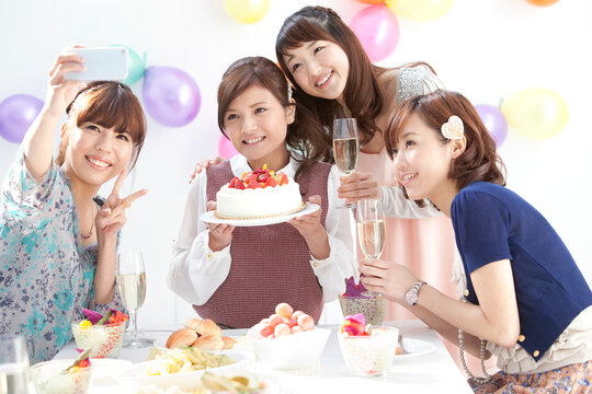 スマートフォンで写真を撮る女性4人