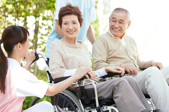 介護士と車いすに乗った中高年男女