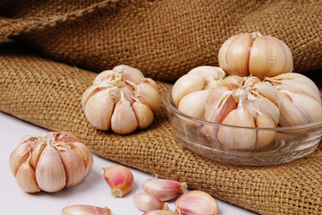 Garlic Cloves and Bulb in glass bowl on hemp sack.