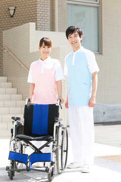 笑顔の男女介護士2人と車いす
