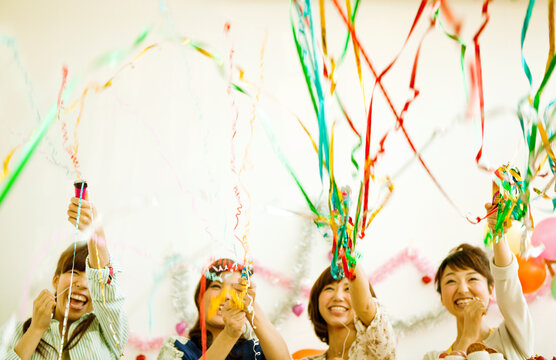 クラッカーを鳴らす若い女性4人