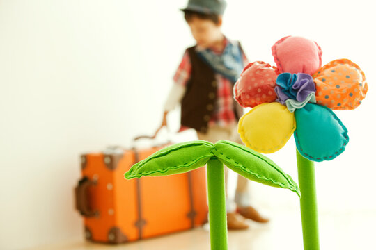 スーツケースを持つ男の子と花のオブジェ