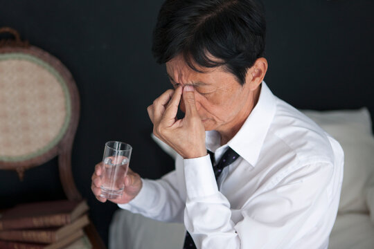 目頭を押さえる中高年男性