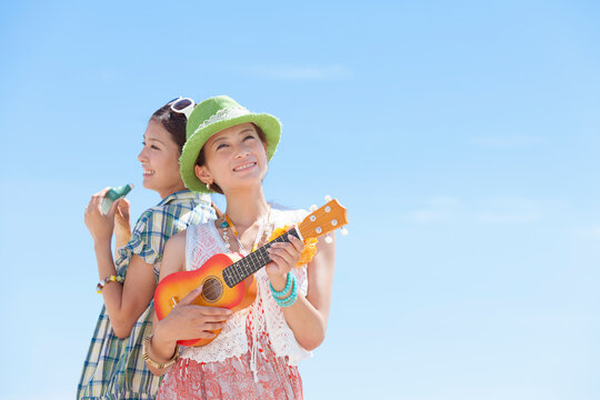 青空の下で楽器を演奏する女性2人