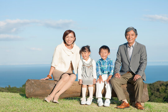丸太に座っている祖父母と孫