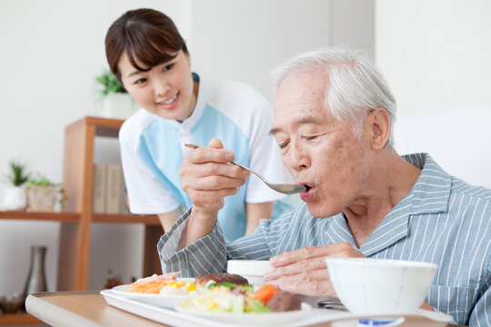 女性介護士と食事をするシニア男性