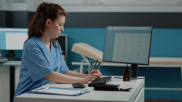 Nurse typing on computer keyboard for consultation and appointment. Medical assistant using technology for healthcare system in doctors office. Specialist working with medical equipment