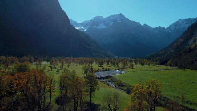 Vibrant maple trees at Ahornboden with colorful red and yellow fall leaves in sunny autumn in the alps mountains in Tyrol, Austria with a forest at Rissach Engtal tourist travel spot. Aerial drone