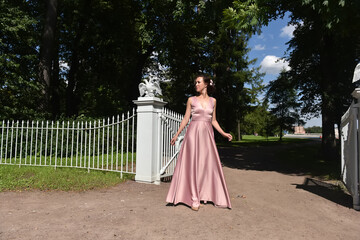 Fototapeta premium elegant brunette woman in pink dress in the park