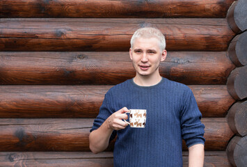 A yang guy with white hair on the background of a log house