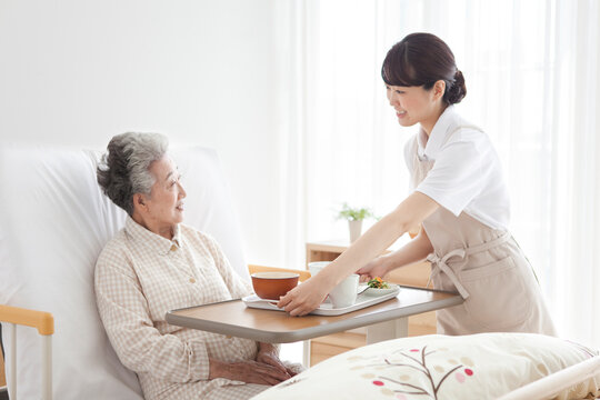 食事を持ってくる女性とシニア女性