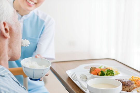 食事介助をする女性介護士とシニア男性