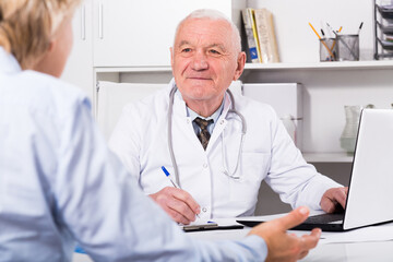 Mature female client visiting consultation with man doctor in hospital