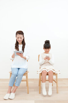 タブレットPC等を操作する母娘
