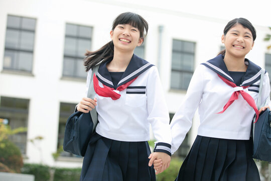 手をつないで走る女子校生2人