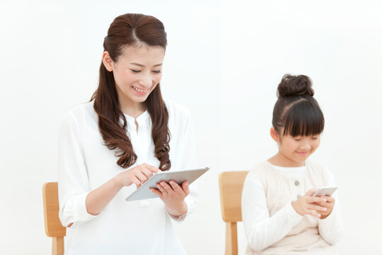 タブレットPC等を操作する母娘