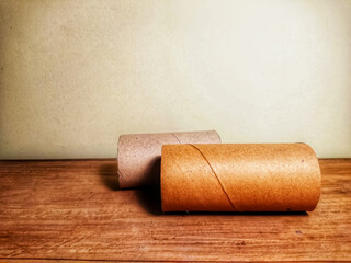 Two cardboard cylinders. Background with wooden floor and cream color wall.