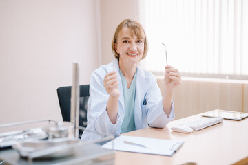 A female dentist sitting in an office showing a tooth extraction device