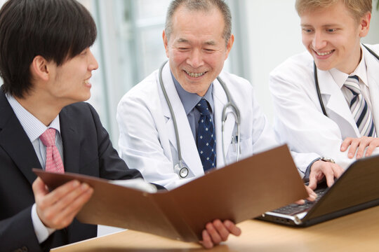 医師に資料を見せるビジネスマン